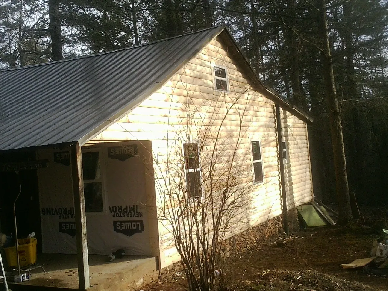 Log siding gable end under a dark metal roof edge in Greenwood