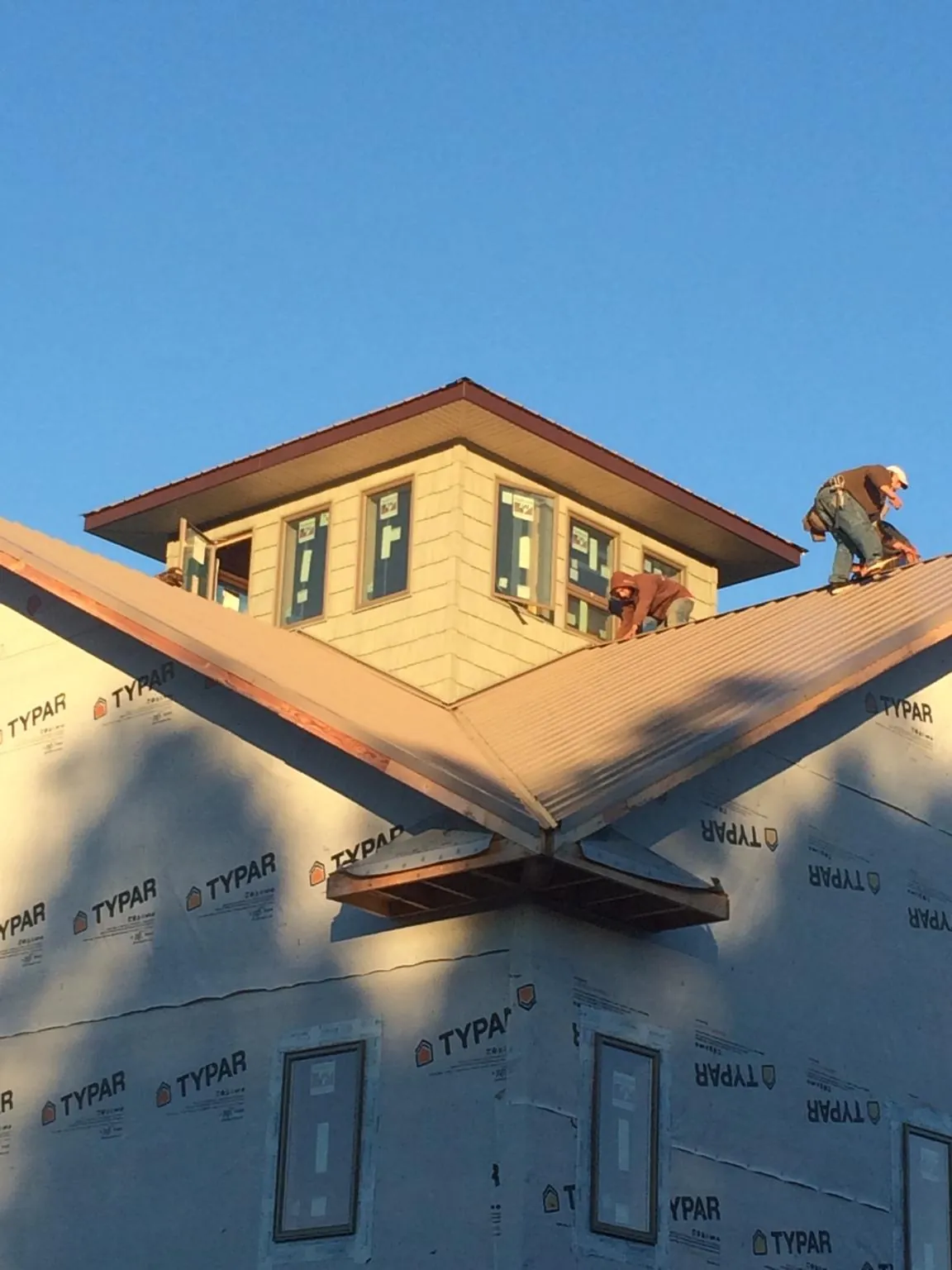 Roofers working around a rooftop cupola on a new metal roof at sunset — Roof Waterproofing in Greenwood by Roofing Brothers